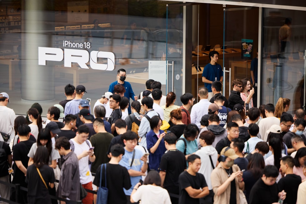 Customers stand outside Apple Jing’an waiting for the store to open as team members look on.